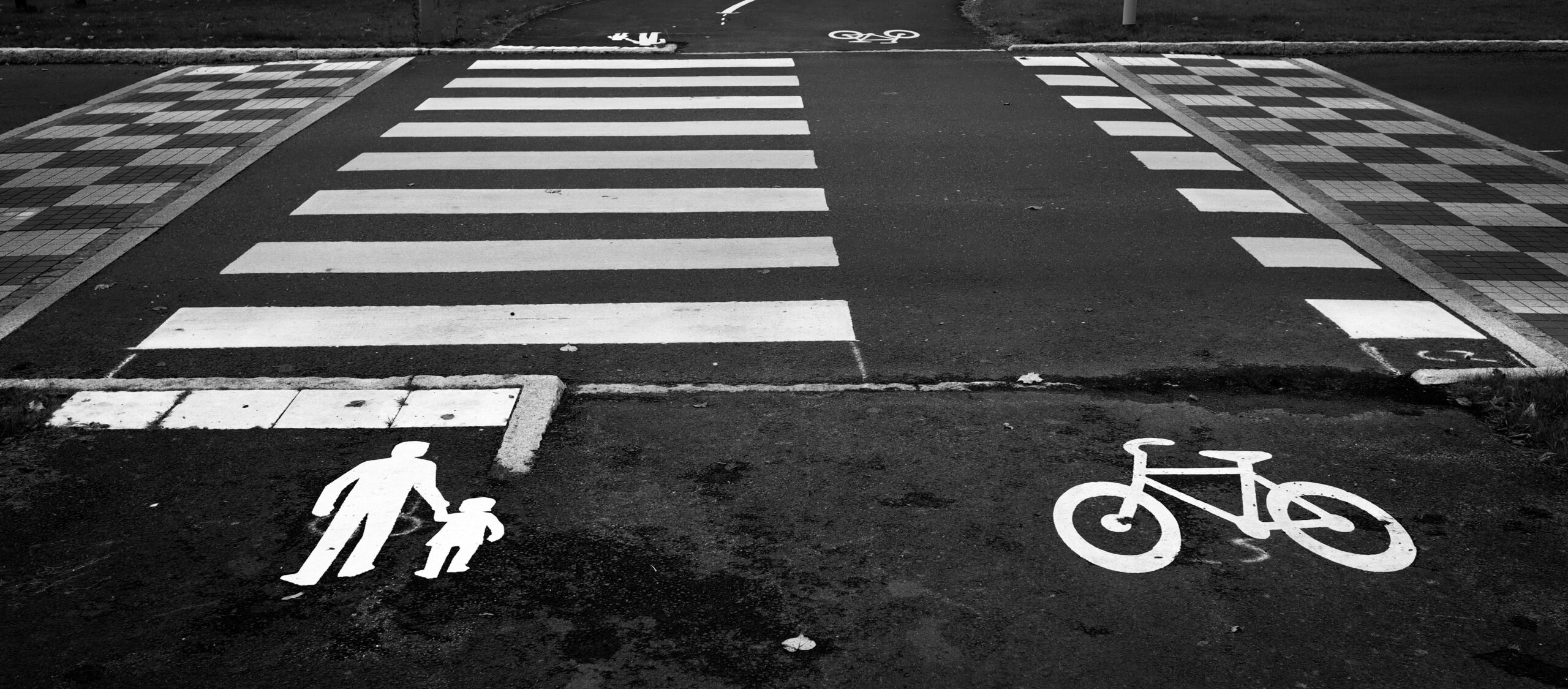Black and white photo of a pedestrian and bicycle crossing with clear road markings.